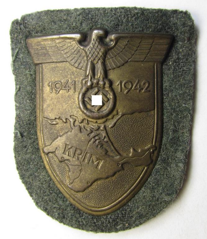 Attractive, WH (Heeres o. Waffen-SS) 'Krim'-campaign-shield that comes mounted onto its original, field-grey-coloured 'backing' and that comes in an issued-, minimally worn and/or carefully tunic-removed-, condition