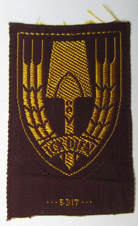 Neat - and nicely 'BeVo-woven'-like - Dutch WWII-period, labour service ie. 'Nederlandse Arbeidsdienst' (or: NAD) cap-badge entitled: 'Ick Dien' and that comes in a 'virtually mint- ie. unissued', condition