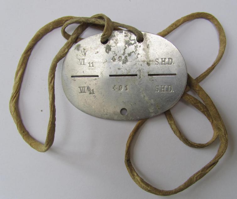 Aluminium-based, 'S.H.D.'- (ie. 'Sicherheits- u. Hilfsdienst'-) related ID-disc that comes mounted on its original cord as issued and/or worn, bearing the neatly stamped unit-signification that reads: 'VI 11 491 S.H.D.'