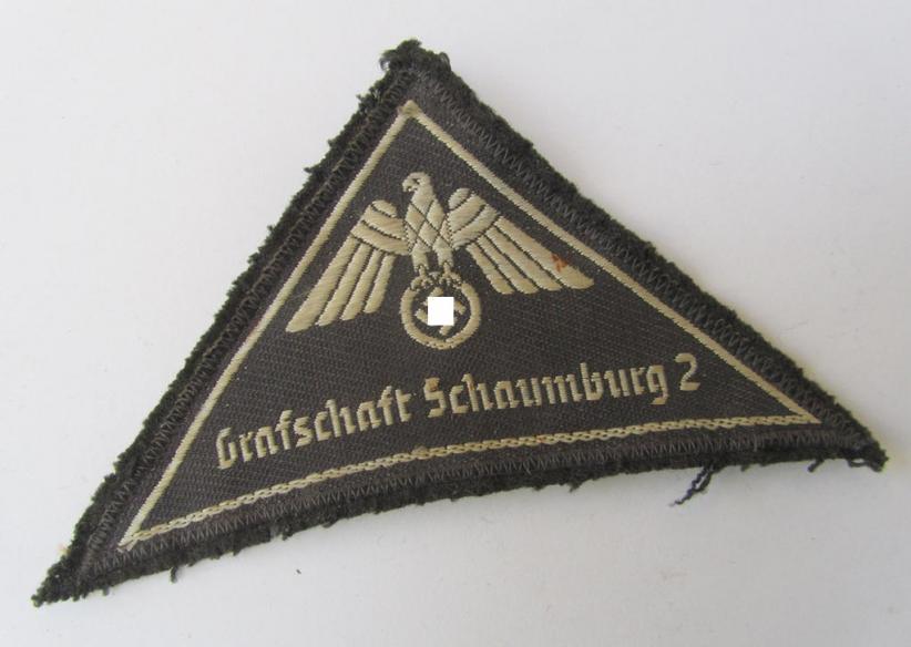 Neat, German Red Cross (ie. 'Deutsches Rotes Kreuz' or 'DRK') greyish-coloured and/or triangular-shaped uniform-eagle entitled: 'Grafschaft Schaumburg 2', as executed in the neat 'BeVo'-weave pattern 