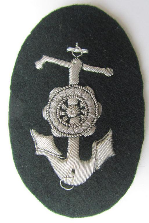 Superb, WH (Heeres) trade- or special-career insignia, being a very detailed- and/or hand-embroidered example on darker-green-coloured wool, as was intended for usage by a: 'Steuermann' (ie. enigineer boat-pilot or helmsman)