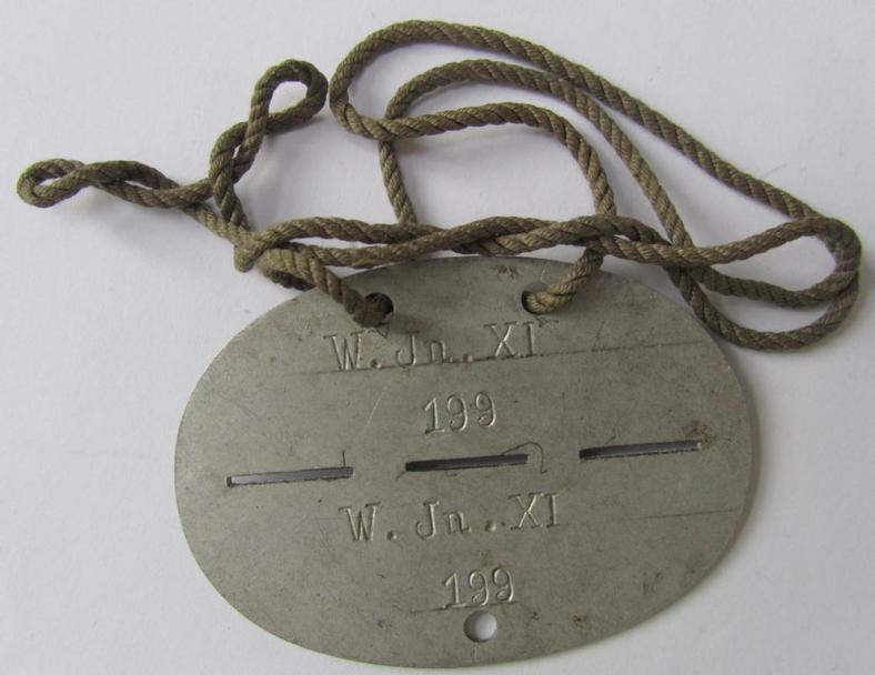 Neat, aluminium-based-, WH (Heeres-) ie. 'Wehrkreis'-related ID-disc, bearing the clearly stamped unit-designation: 'W.Jn.XI' and that comes mounted on its period-attached cord as issued and/or worn