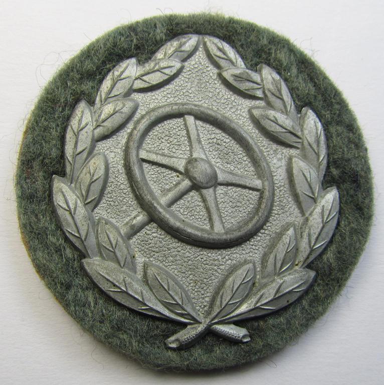 WH (Heeres- ie. Waffen-SS) so-called: 'Kraftfahrbewährungs-Abzeichen in Silber' (or: drivers' proficiency-badge in silver) that comes mounted onto its piece of field-grey-coloured wool as most certainly issued- albeit simply never worn, condition