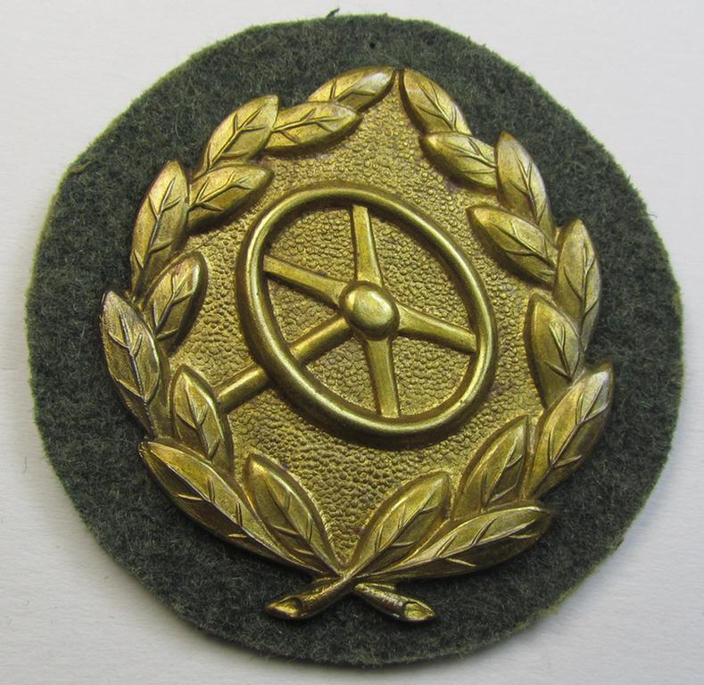 WH (Heeres- ie. Waffen-SS) so-called: 'Kraftfahrbewährungs-Abzeichen in Gold' (or: drivers' proficiency-badge in gold) that comes mounted onto its piece of field-grey-coloured wool as most certainly issued- albeit simply never worn, condition