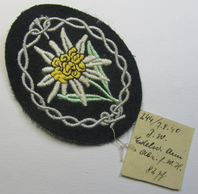 Attractive, WH (Heeres) EM- (ie. NCO-) type, so-called: 'Edelweiss'-armpatch, being a machine-embroidered 'Muster'-piece as intended for usage by the: 'Gebirgsjäger-Truppen' and that comes with its period-attached 'inventory-etiket'