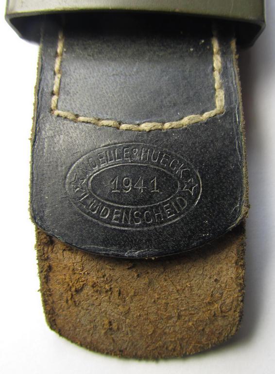 Attractive, WH (Heeres) field-grey-coloured- and/or steel-based belt-buckle being a neatly maker- (ie. 'Noelle & Hueck'-) marked- and/or: '1941'-dated example that comes mounted onto its (black-coloured) leather-based tab