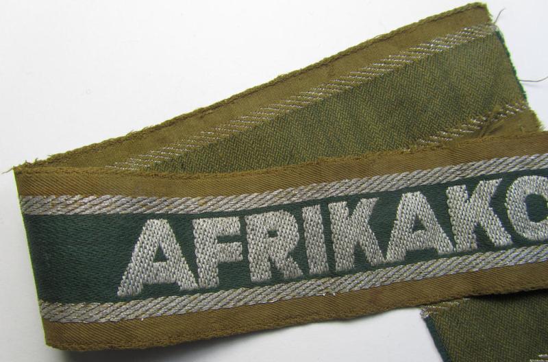 Attractive, 'BeVo'-like cuff-title (ie. 'Ärmelstreifen') entitled: 'Afrikakorps' being a with certainty issued and truly worn example that comes in an overall nice- (ie. minimally shortened- and once tunic-attached-), condition