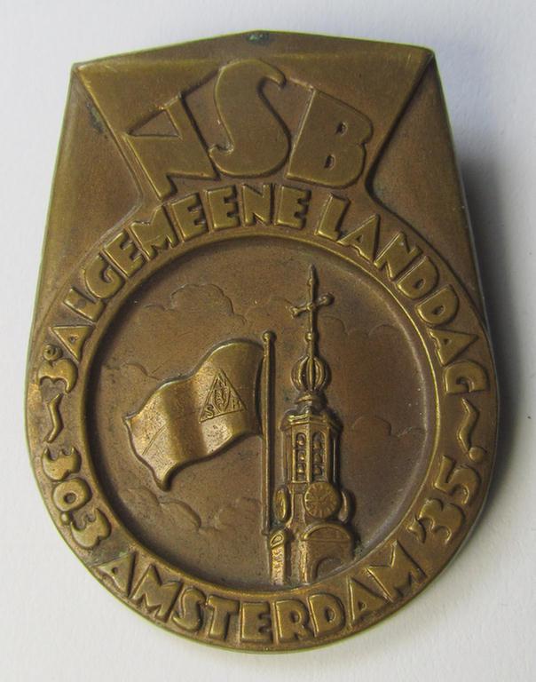 Dutch NSB-party-related: 'Landdag'-lapel-pin (ie. 'Veranstaltungsabzeichen' ie. tinnie) that is executed in golden-toned- (ie. copper-based-) metal and that is depicting the text: 'NSB - Algemene Landdag - Amsterdam - 30.3.35'