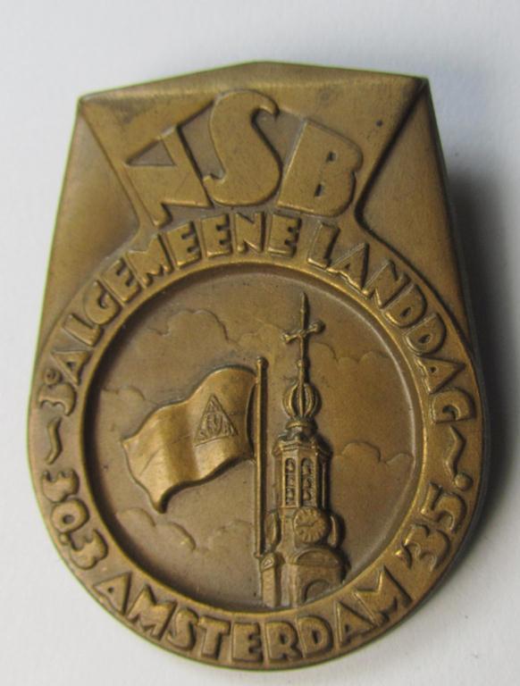Dutch NSB-party-related: 'Landdag'-lapel-pin (ie. 'Veranstaltungsabzeichen' ie. tinnie) that is executed in golden-toned- (ie. copper-based-) metal and that is depicting the text: 'NSB - Algemene Landdag - Amsterdam - 30.3.35'