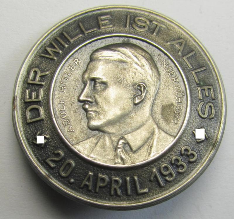 Superb, silverish-coloured and tin-based, N.S.D.A.P.-related day-badge (ie. 'tinnie' or: 'Veranstaltungsabzeichen') being a commemorative example that shows a portrait of Adolf Hitler surrounded by the text: 'Der Wille ist Alles - 20 April 1933'