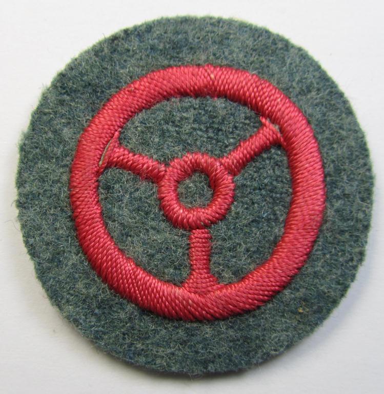 Fire-police- (ie. 'Feuerwehr'-) related, neatly hand-embroidered trade- ie. special-career patch (ie. 'Laufbahn- o. Tätigkeitsabzeichen') depicting a pinkish-coloured steering-wheel as was intended for: 'Kraftfahrpersonal'