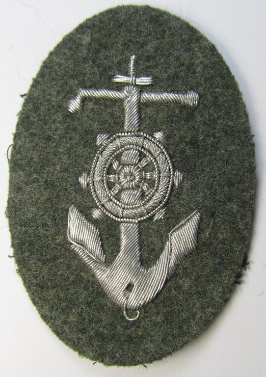 Superb, WH (Heeres) trade- and/or special-career insignia, being a detailed- and/or neatly hand-embroidered example as executed on field-grey-coloured wool, as was intended for a: 'Steuermann' (ie. enigineer-boat-pilot or helmsman)