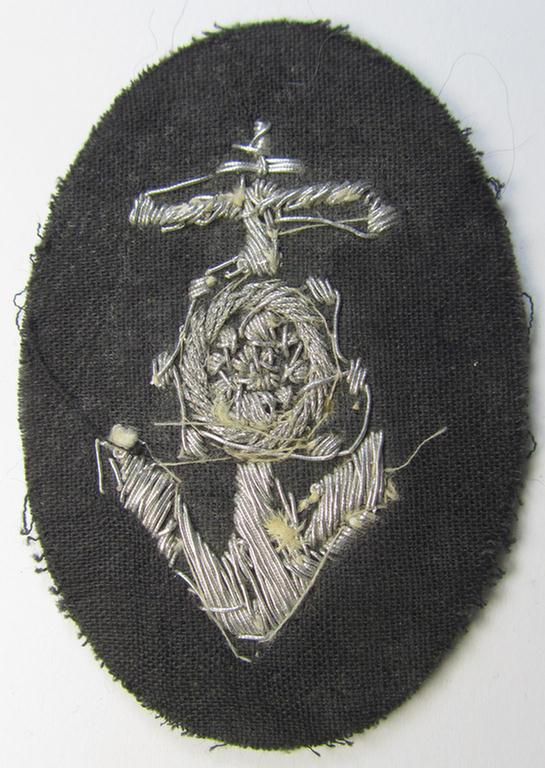 Superb, WH (Heeres) trade- and/or special-career insignia, being a detailed- and/or neatly hand-embroidered example as executed on field-grey-coloured wool, as was intended for a: 'Steuermann' (ie. enigineer-boat-pilot or helmsman)