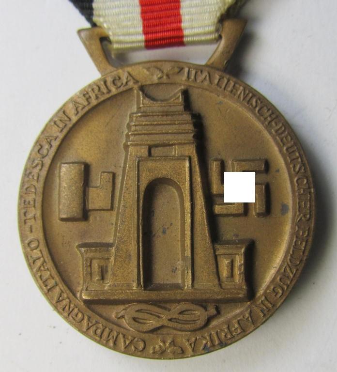 Superb, golden-bronze-coloured- (and I deem 'Buntmetall'-based-) example of a: 'Deutsch-Italienische Feldzugsmedaille' (or: German-Italian campaign medal) that comes mounted onto its (regular-sized) piece of original (albeit minimally faded) ribbon