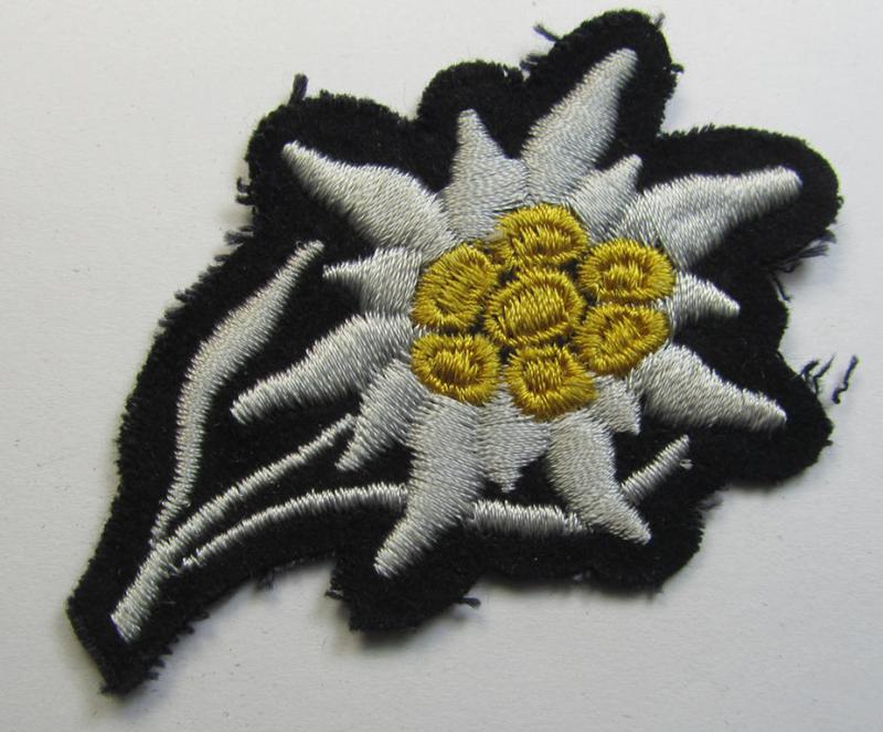Attractive, Waffen-SS-pattern black-coloured M43-cap-insignia (ie. 'Mützenabzeichen') depicting an: 'Edelweiss'-flower as was specifically used by the various 'Gebirgsjäger'- (ie. mountain-troops-) related divisional-staff