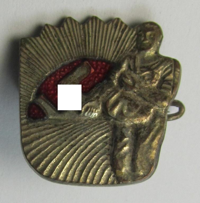 Attractive, silverish-coloured and 'Buntmetall'-based, N.S.D.A.P.-related lapel-pin (ie. 'Mitgliedsabzeichen') being a commemorative example that shows a sowing farmer-figure surrounded by an enamelled: 'Sunburst'-swastika