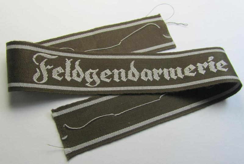 Superb - and scarcely encountered! - example of a WH (Heeres) cuff-title ie. armband (ie. 'Ärmelstreifen') entitled: 'Feldgendarmerie' (being a typical 'semi-BeVo'-woven!) example that comes in a full length- ie. non-shortened, condition