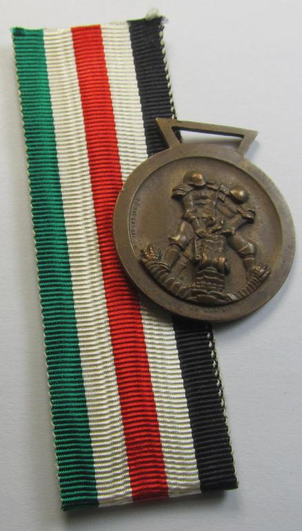 Attractive, golden-bronze-coloured- (and I deem 'Buntmetall'-based-) example of a: 'Deutsch-Italienische Feldzugsmedaille' (or: German-Italian campaign medal) that comes together with its (non-confectioned and 'mint') piece of original ribbon