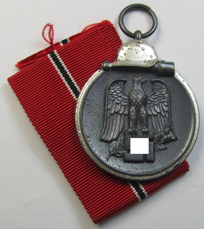 Attractive medal-set: 'Winterschlacht im Osten 1941-42' being a maker- (ie. '107'-) marked- (and/or 'Feinzink'-based) specimen by the maker: 'Carl Wild - Hamburg' and that comes together with its (non-confectioned) ribbon (ie. 'Bandabschnitt')
