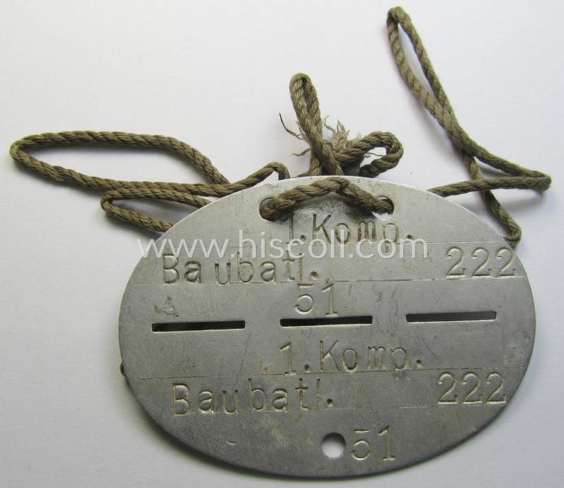 Aluminium-based, WH (Heeres) ie. 'Pioniere- o. Bau-Truppen'-related ID-disc bearing the clearly stamped unit-designation: '1. Komp.Baubatl. 222' and that comes mounted on its period cord as issued and worn