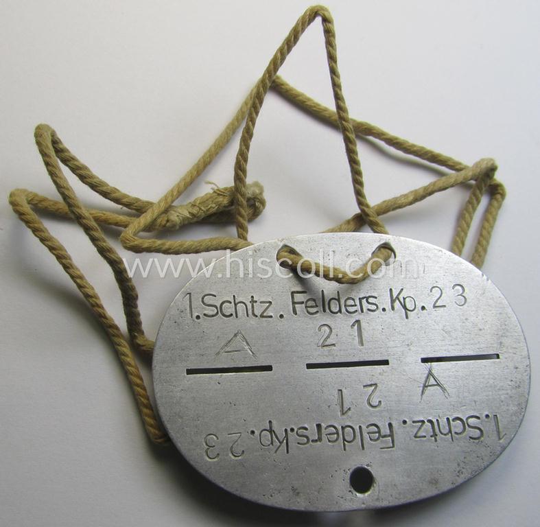 Aluminium-based, WH (Heeres) ie. 'Infanterie-Truppen'-related ID-disc bearing the clearly stamped unit-designation: '1. Schtz.Felders.Kp. 23' and that comes mounted onto its period cord as issued and worn
