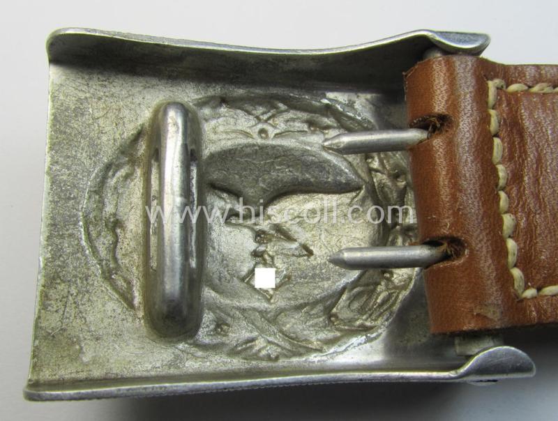 Attractive, WH (Luftwaffe) silver-coloured and aluminium-based belt-buckle, being a maker- (ie. 'F.W. Assmann & Söhne'-) marked example that comes mounted onto its leather-based tab and that comes in a minimally used condition