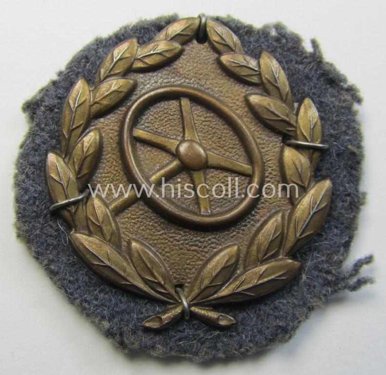 WH (Luftwaffe) so-called: 'Kraftfahrbewährungs-Abzeichen in Bronze' (or: bronze-class drivers'-proficiency-badge) that comes mounted onto its piece of blue-grey-coloured wool as most certainly issued- and/or clearly worn, condition