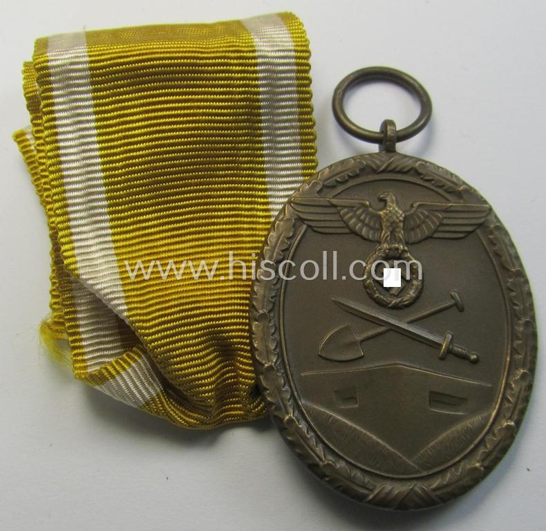 Medal-set: 'Deutsches Schutzwall Ehrenzeichen' (aka: 'Westwall'-medal) being a non-maker-marked- and/or: 'Buntmetall'-based specimen that comes together with its period- (and neatly folded ie. pre-confectioned) ribbon (ie. 'Bandabschnitt')