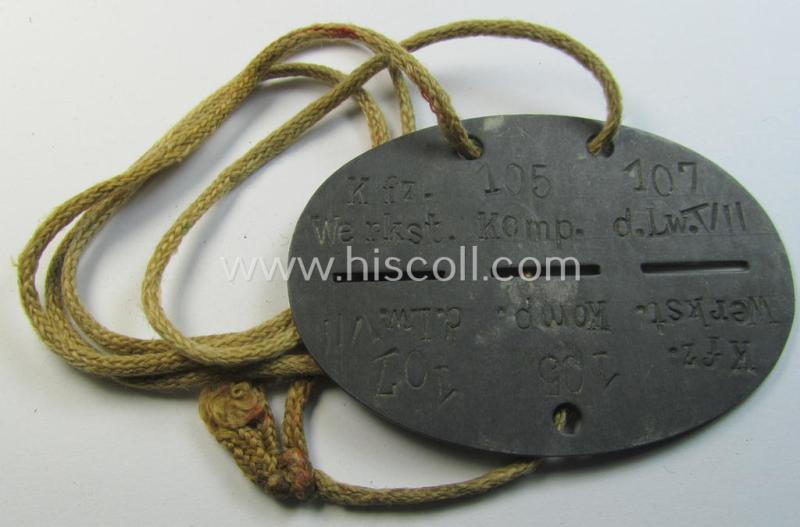 Attractive - and typical zinc-based - WH (Luftwaffe) related ID-disc (ie. 'Erkennungsmarke') bearing the stamped unit-designation that simply reads: 'Kfz.Werkst.Komp.der Lw.VII 107' and that comes mounted onto its period cord as issued & worn