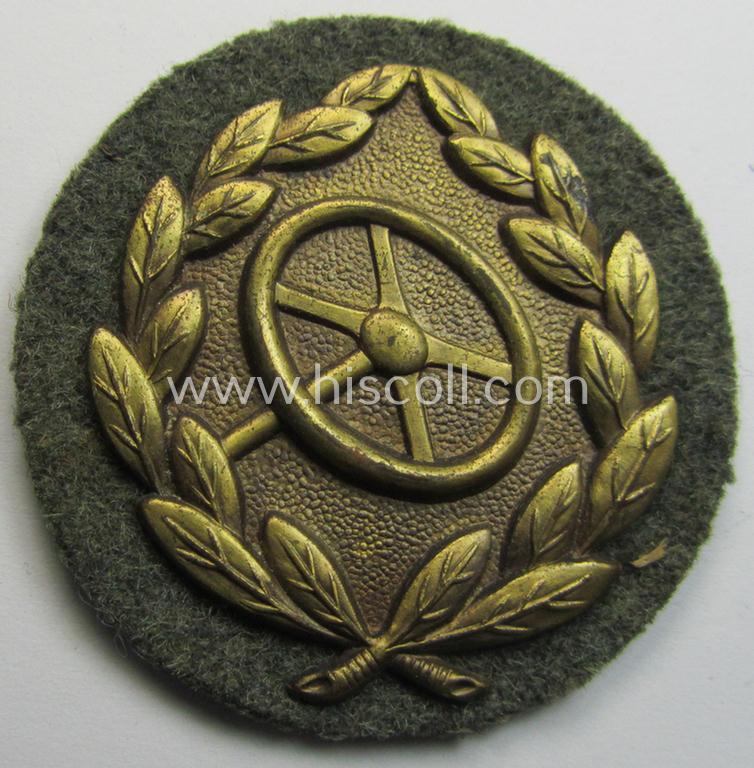 WH (Heeres- ie. Waffen-SS) so-called: 'Kraftfahrbewährungs-Abzeichen in Gold' (or: golden-class drivers' proficiency-badge) that comes mounted onto its piece of field-grey-coloured wool and that comes as probably issued- but never worn, condition