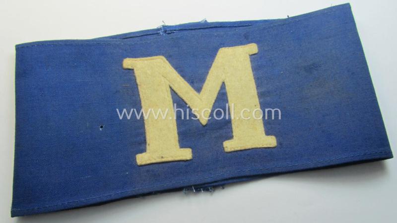 Neat, linnen-based- and/or blue-coloured armband (ie. 'Armbinde') depicting a felt-woolen-based, capital 'M'-character as was presumably intended for staff-members (ie. 'Melder') of the German RLB (ie. 'Reichsluftschutz-Bund')