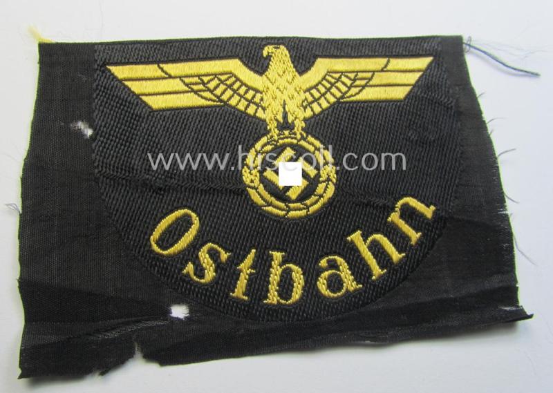 RB- ('Reichsbahn'-) related arm-eagle (ie. 'Ärmeladler') depicting the text: 'Ostbahn' (as was presumably intended for an official of the: 'Deutsche Reichsbahn' ie. the: 'WVD im Osten' ie.: 'Wehrmacht-Verkehrsdirektion im Osten')