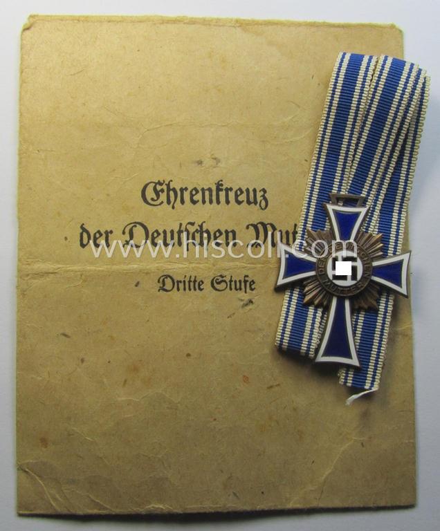 Attractive, 'Ehrenkreuz der deutschen Mutter - dritte Stufe' (or: bronze-class mothers'-cross) that came mounted onto its long-sized ribbon and that came stored in its period pouch (by the maker: 'Ferd. Wagner - Pforzheim')